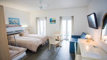 Een hotelkamer met stapelbedden, een bureau, een stoel, een televisie en een plafondventilator.