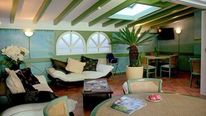 A cozy living room with a sofa, coffee table, and a dining area with chairs and a table. - Hotel Du Port (Villeneuve)