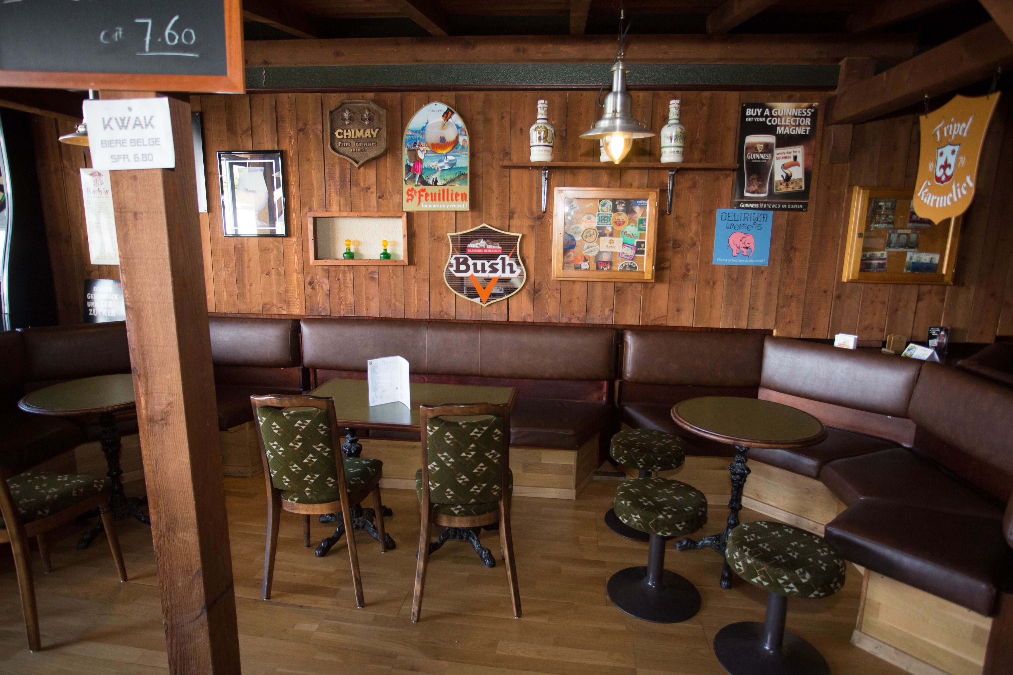 Interior de un restaurante con paredes de madera, diversas opciones de asientos como cabinas y mesas, y varios carteles anunciando comida y bebidas.