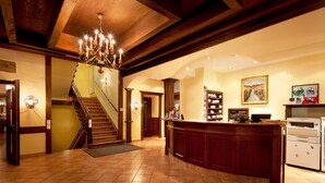 Un vestíbulo amplio con una imponente escalera, un mostrador de recepción y un candelabro.