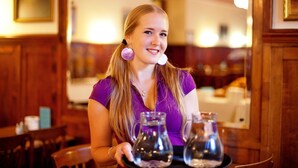 Una persona sentada a una mesa con dos jarras y una bandeja.