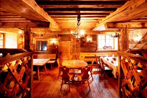 A rustic wooden cabin with a central dining table surrounded by chairs, wooden walls, and a sloped ceiling with exposed beams. - Euro Youth Hotel & Krone (Bad Gastein)