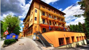 Un hotel de varios pisos con fachada amarilla, balcones y una escalera que conduce a la entrada.