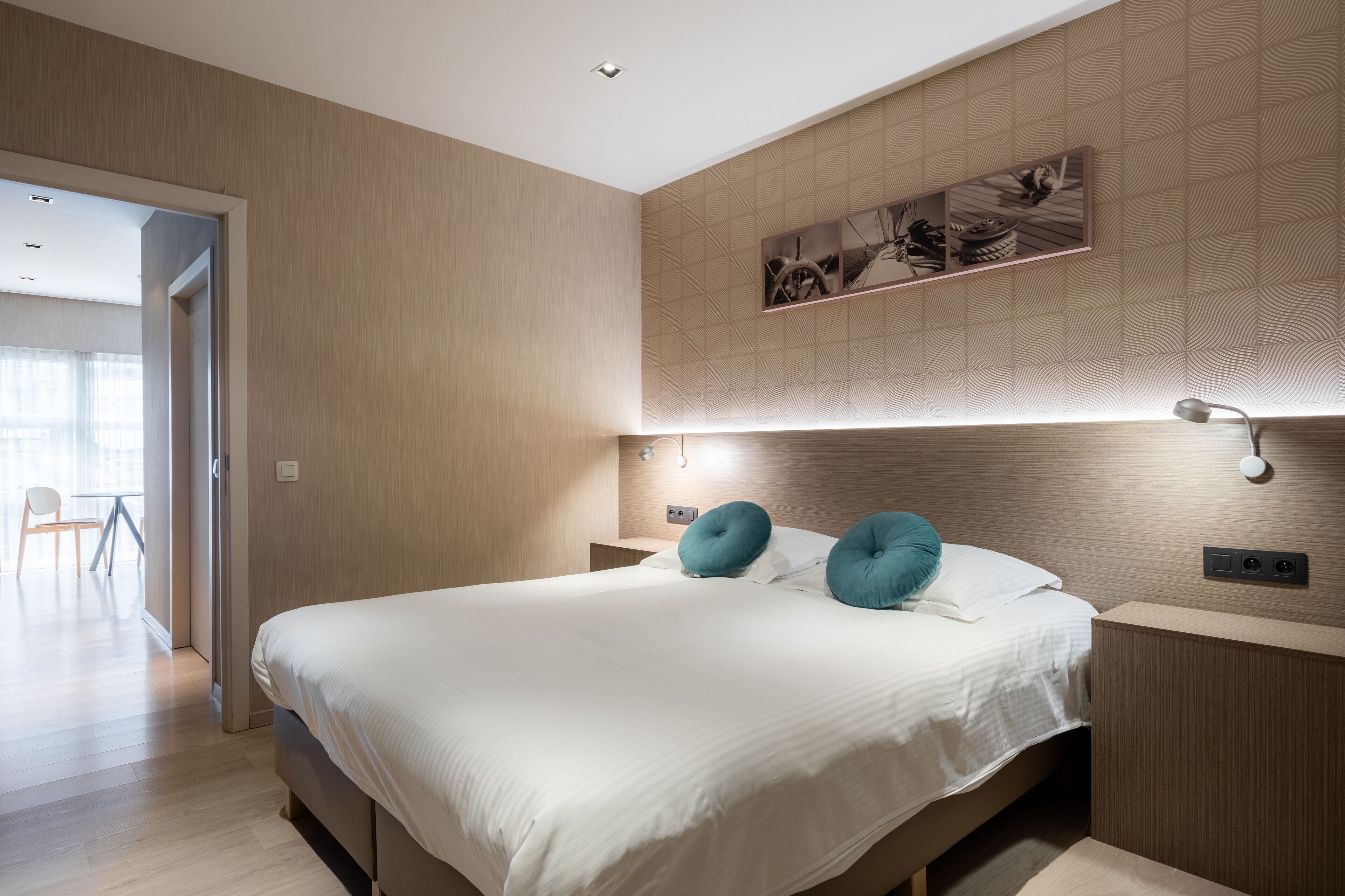 Une chambre d’hôtel moderne avec un grand lit, deux tables de chevet et une œuvre d’art accrochée au mur.