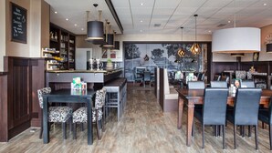 Un restaurant doté d’un bar, de plusieurs tables et de chaises.
