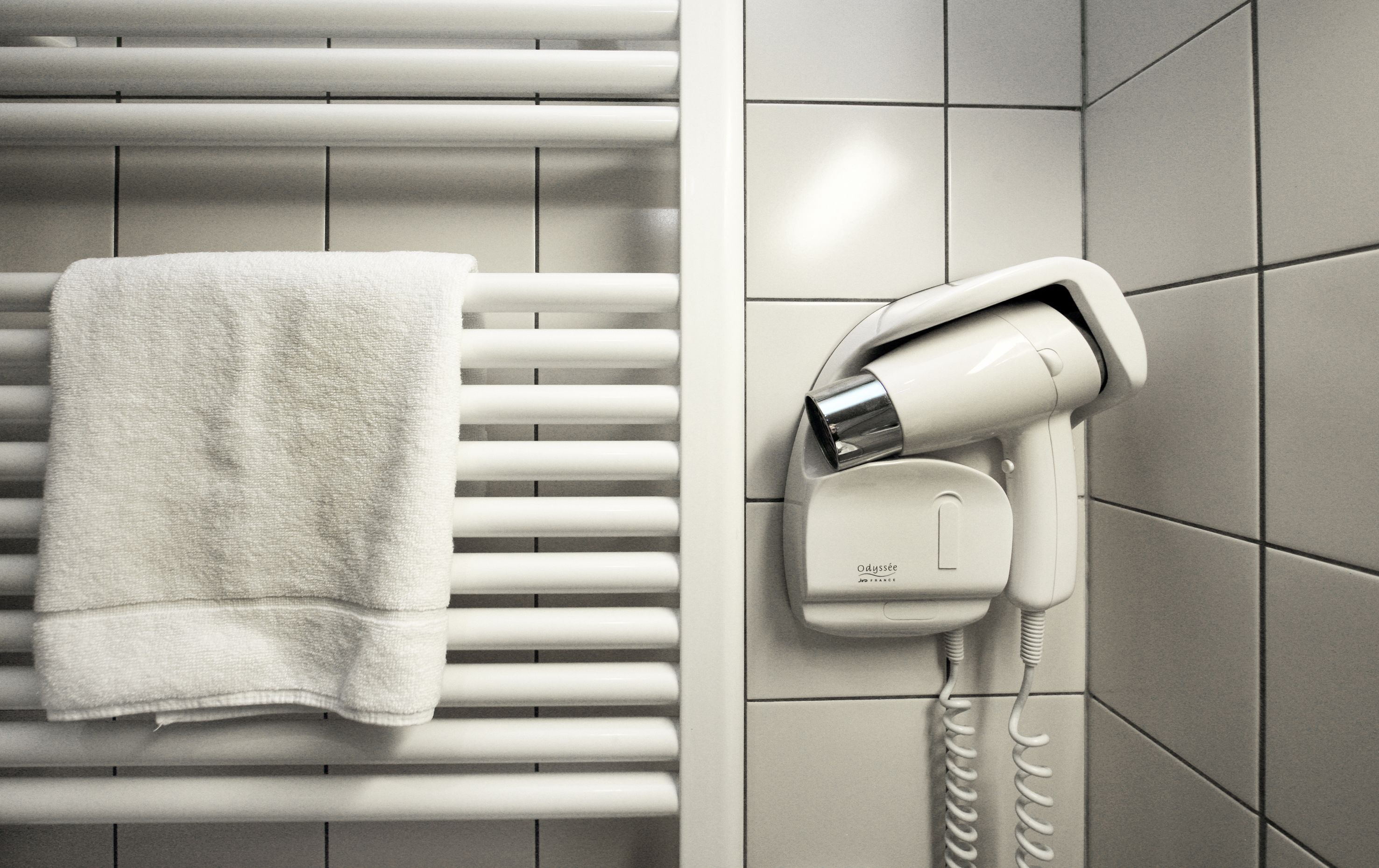 Un baño con un perchero para toallas y un secador de pelo fijado a la pared.