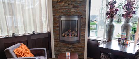 Un salón acogedor con chimenea, asientos cómodos y vistas al exterior.