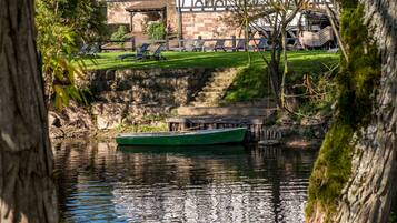 A riverside view with a traditional building, a boat, and a tree in the foreground.