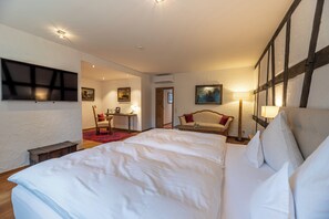 Een hotelkamer met een groot bed, een bureau, een stoel en een televisie aan de muur.