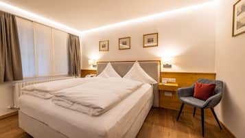 Una habitación de hotel con una cama grande, lámparas de noche, una mesita de madera y una silla.