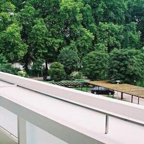 A view of a green park with trees and a car parked under a shelter.