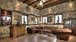 A spacious room with stone walls, wooden furniture, and large windows.