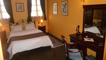 A hotel room with a large bed, a wooden dresser, a chair, and a mirror.