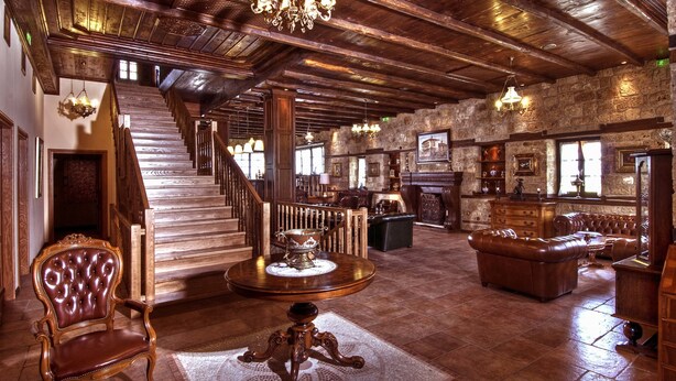 A spacious room with a grand staircase, wooden furniture, and a chandelier.