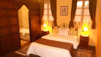 Habitación de hotel con una cama grande, dos mesitas de noche con lámparas, un armario de madera y un cuadro enmarcado en la pared.