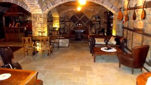 A stone-walled interior with arched ceilings, wooden furniture, and a central table.