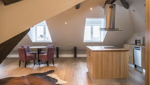 A modern kitchen with a central island, wooden flooring, and a dining area with striped chairs. - Donners Hotel (Visby)