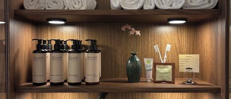 Ein Hotelbad mit Holzböden, auf denen Handtücher, Toilettenartikel und eine Vase mit Blumen stehen.