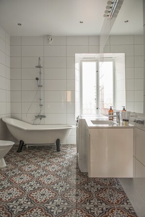 A modern bathroom with a freestanding bathtub, a sink, and a toilet. - Donners Hotel (Visby)