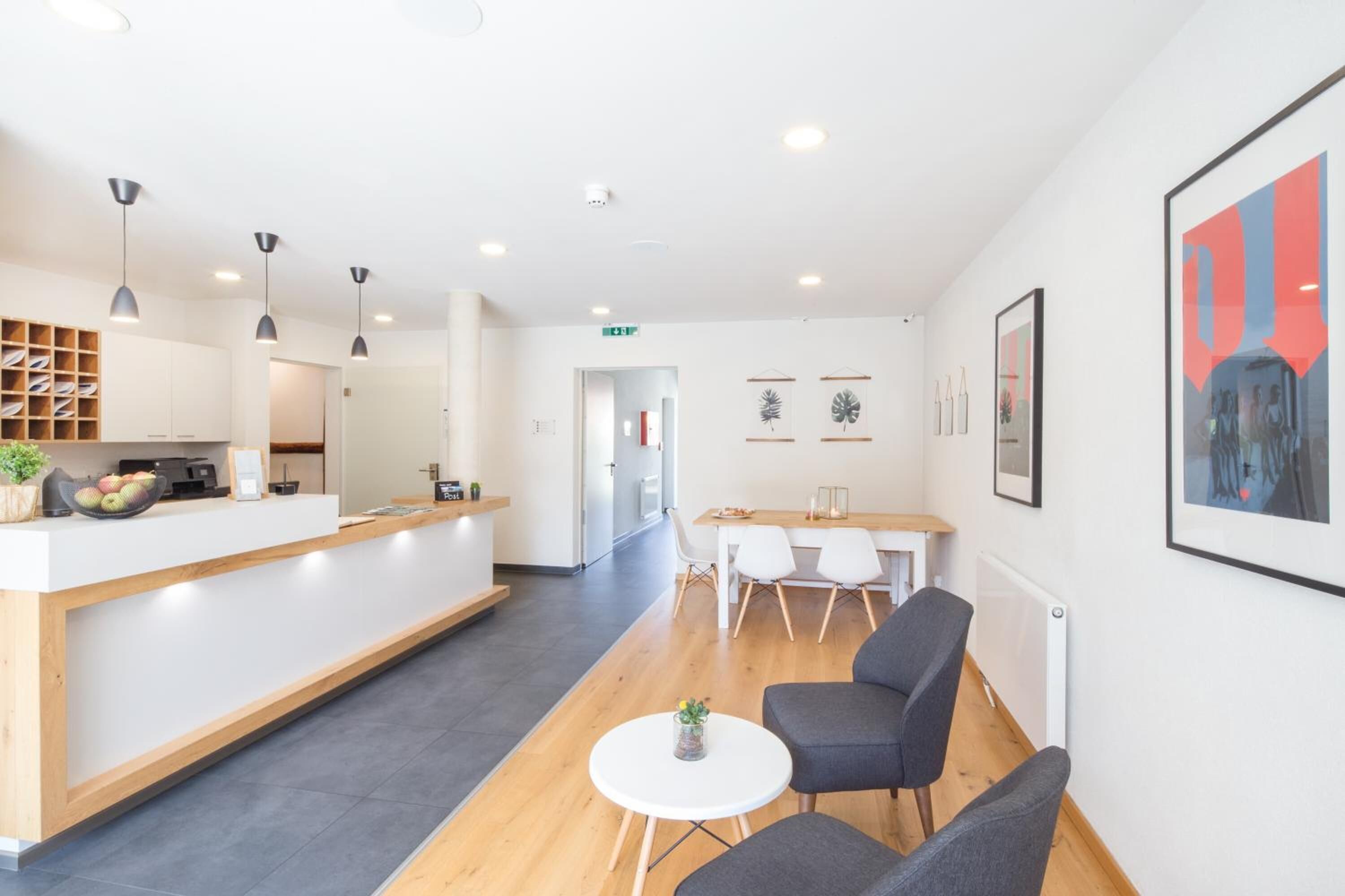 Un hall d’hôtel moderne avec un comptoir d’accueil, un espace salon et des œuvres d’art accrochées aux murs.