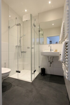 A modern bathroom with a glass-enclosed shower, a white sink, and a mirror. - Adler Hotel & Gasthaus (Nonnenhorn)