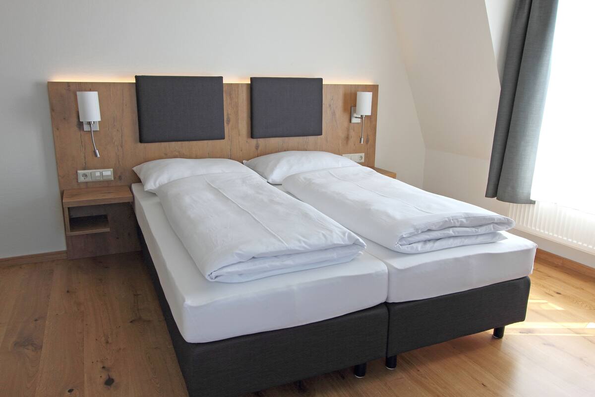 A double bed with a wooden headboard, two bedside tables, and a nightstand.