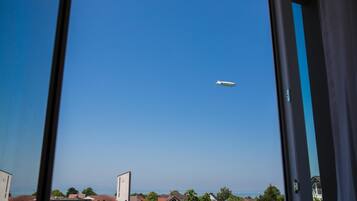 A view of a cityscape with a clear blue sky and a plane flying in the distance.