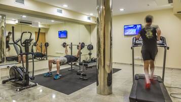 A gym with exercise equipment, a treadmill, and a mirrored wall.