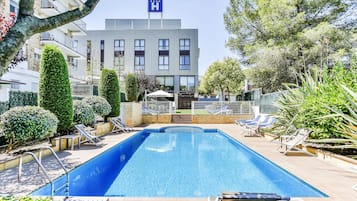 Una piscina al aire libre, sillones reclinables de piscina
