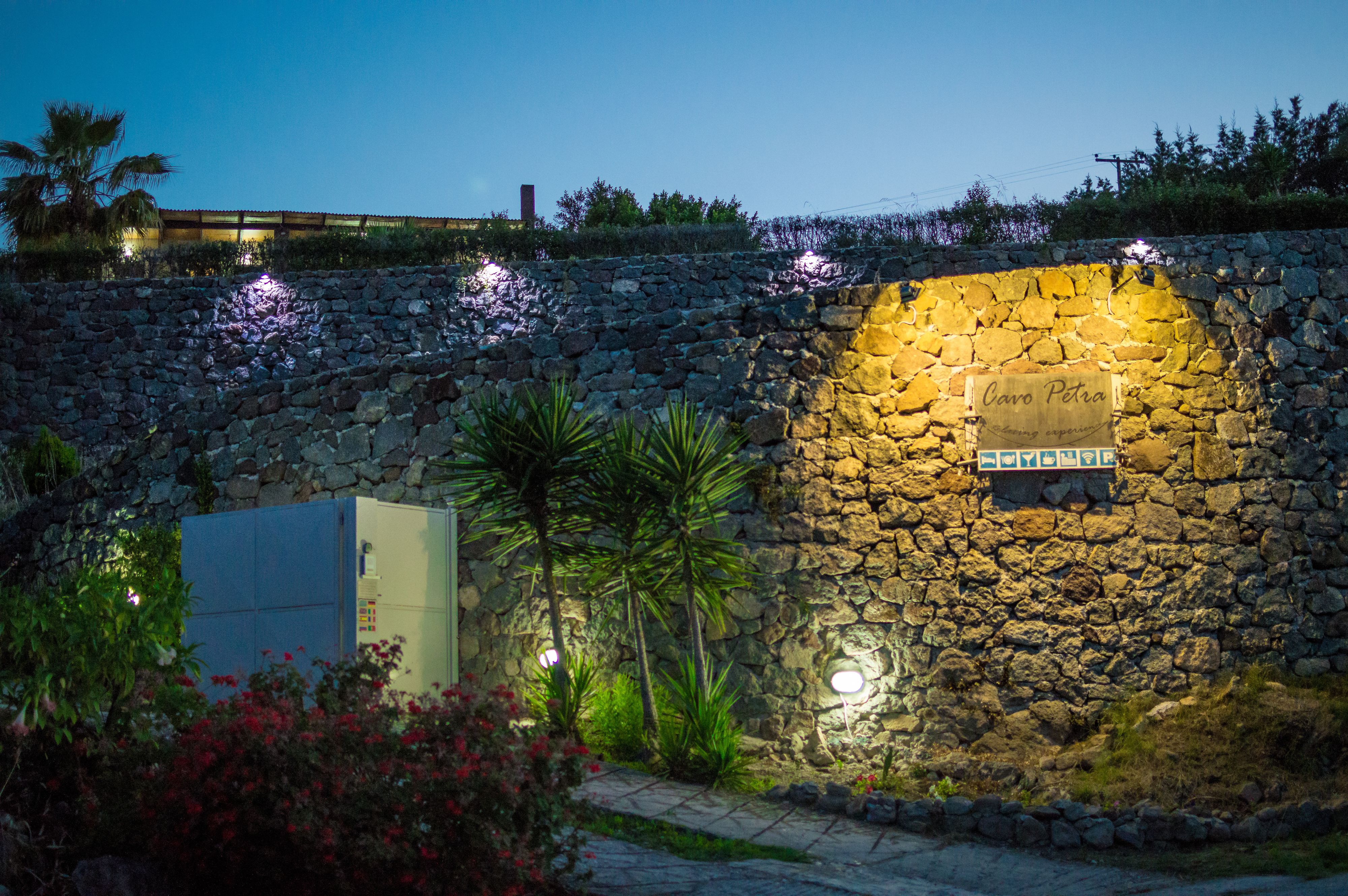 Un muro de piedra con un letrero que dice "Cavo Petra" y un camino que lleva a un edificio.
