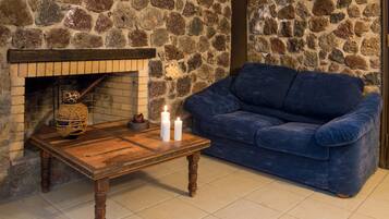 Un muro in pietra, un tavolo di legno con candele e un divano blu in una stanza.