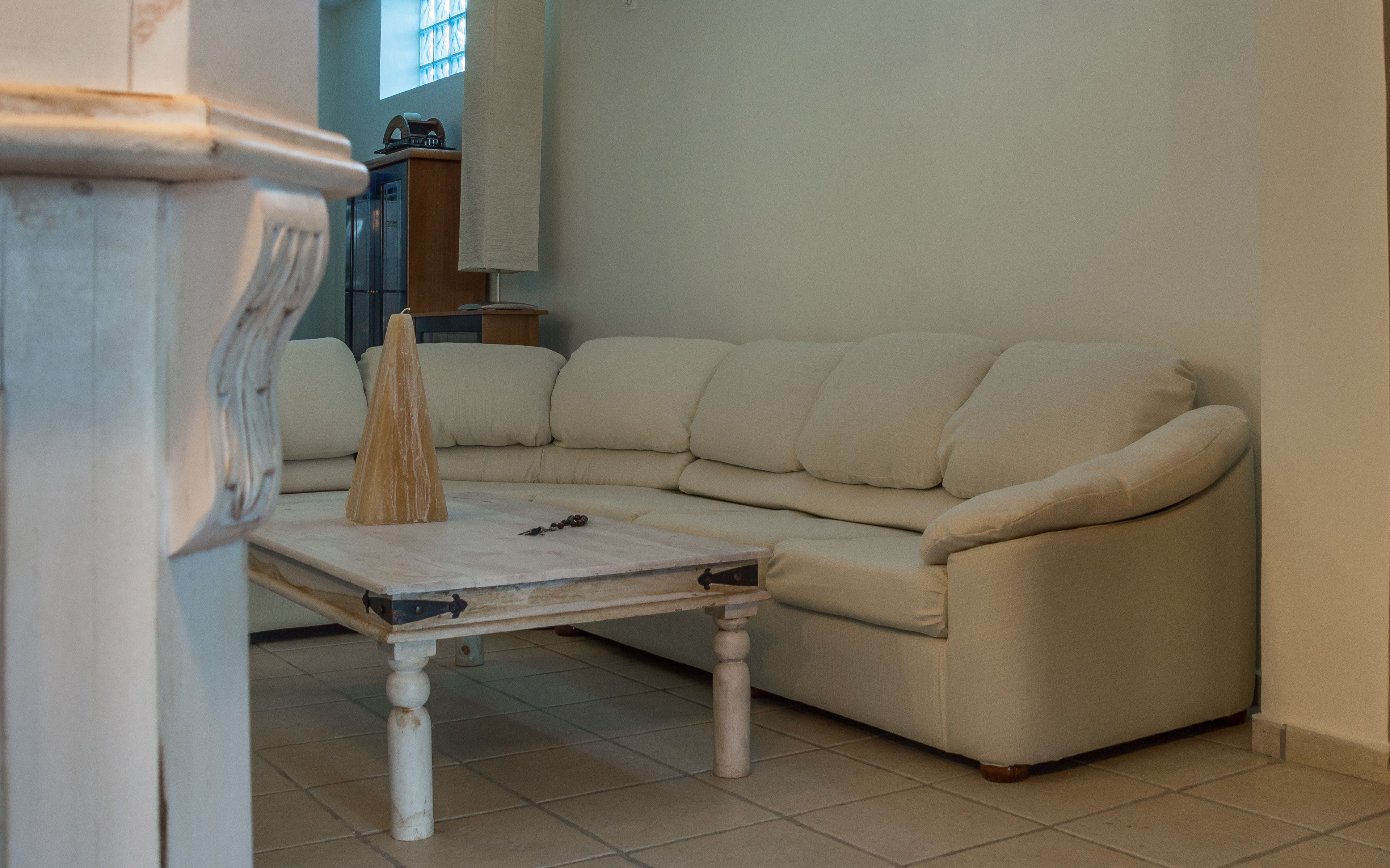 Una sala de estar con un sofá color beige, una mesita blanca y un aparador de madera.