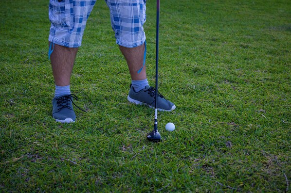 A close-up of a golf club and a golf ball on a grassy surface. - Cavo Petra (Troizinia)