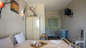 A hotel room with a bed, a desk, a chair, a TV, and a wardrobe. - Cavo Petra (Troizinia)