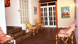 A covered outdoor seating area with wooden chairs and a door leading to an interior space. - Villa Flamboyan (Lauro de Freitas)
