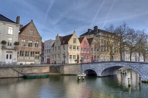 A stone bridge over a calm river with historic buildings on either side. - Hotel Adornes (Bruges)