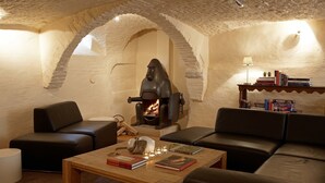 A cozy living room with a fireplace, leather sofas, a coffee table with books and candles, and a bookshelf. - Hotel Adornes (Bruges)