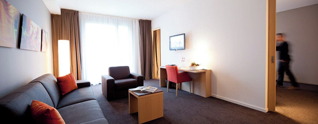Een hotelkamer met een bank, een bureau, een stoel en een salontafel.