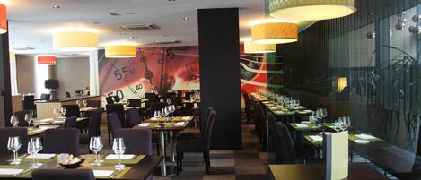 A restaurant with multiple dining tables, chairs, and a large mural on the wall.