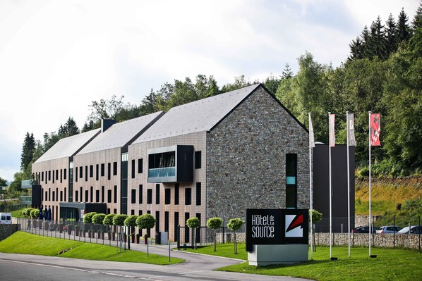 Un hôtel moderne avec une façade en pierre et une enseigne indiquant « Hôtel de Source ».