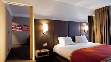 Habitación de hotel con cama, mesitas de noche y vista a la ciudad a través de la ventana.