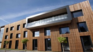 Un edificio moderno con facciata in legno, ampie finestre e tetto piatto.