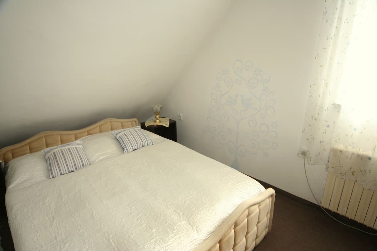 A bedroom with a bed, a nightstand, and a wall with a floral pattern.