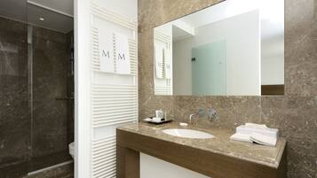 A modern bathroom with a marble vanity, a large mirror, and a glass shower enclosure.