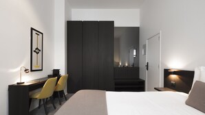Una habitación de hotel moderna con cama, escritorio, sillas y armario.