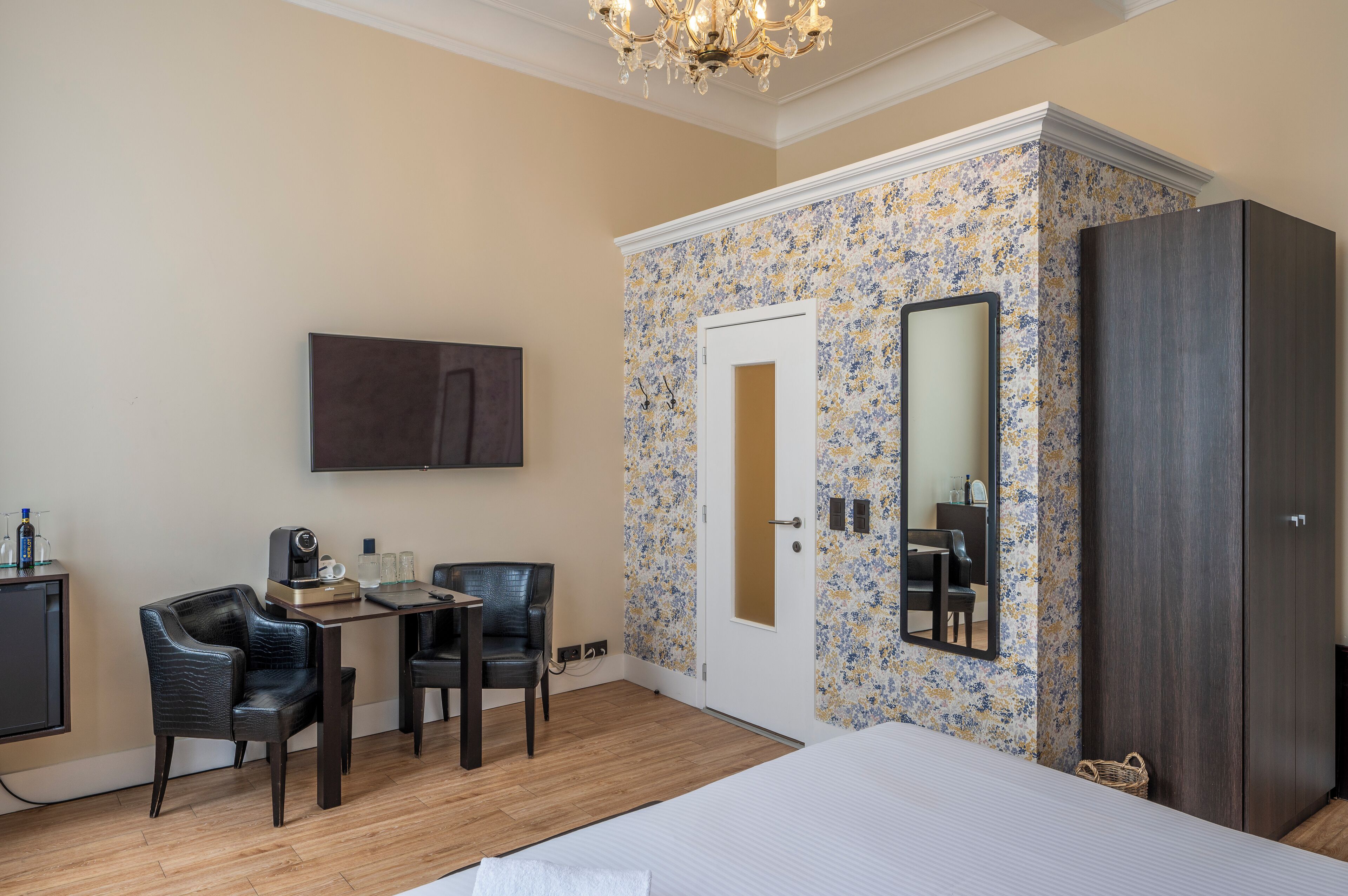 Habitación de hotel con cama, escritorio con silla, televisor, armario y puerta con espejo.