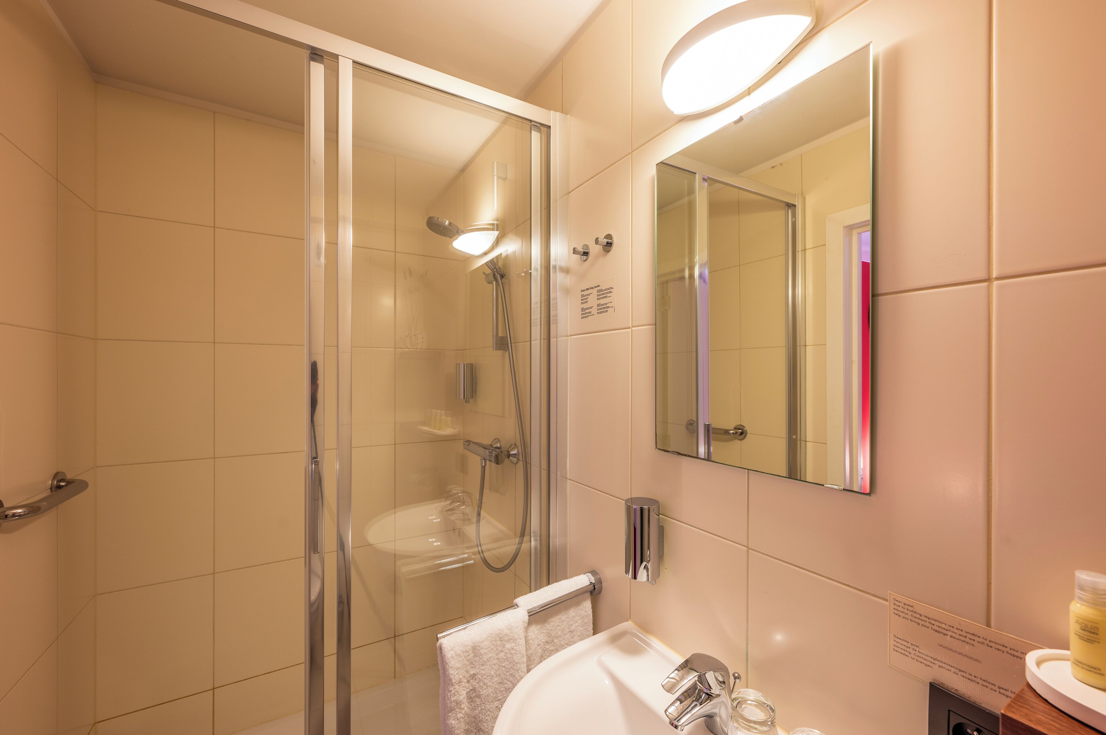 A modern bathroom with a glass-enclosed shower, a sink, and a mirror.