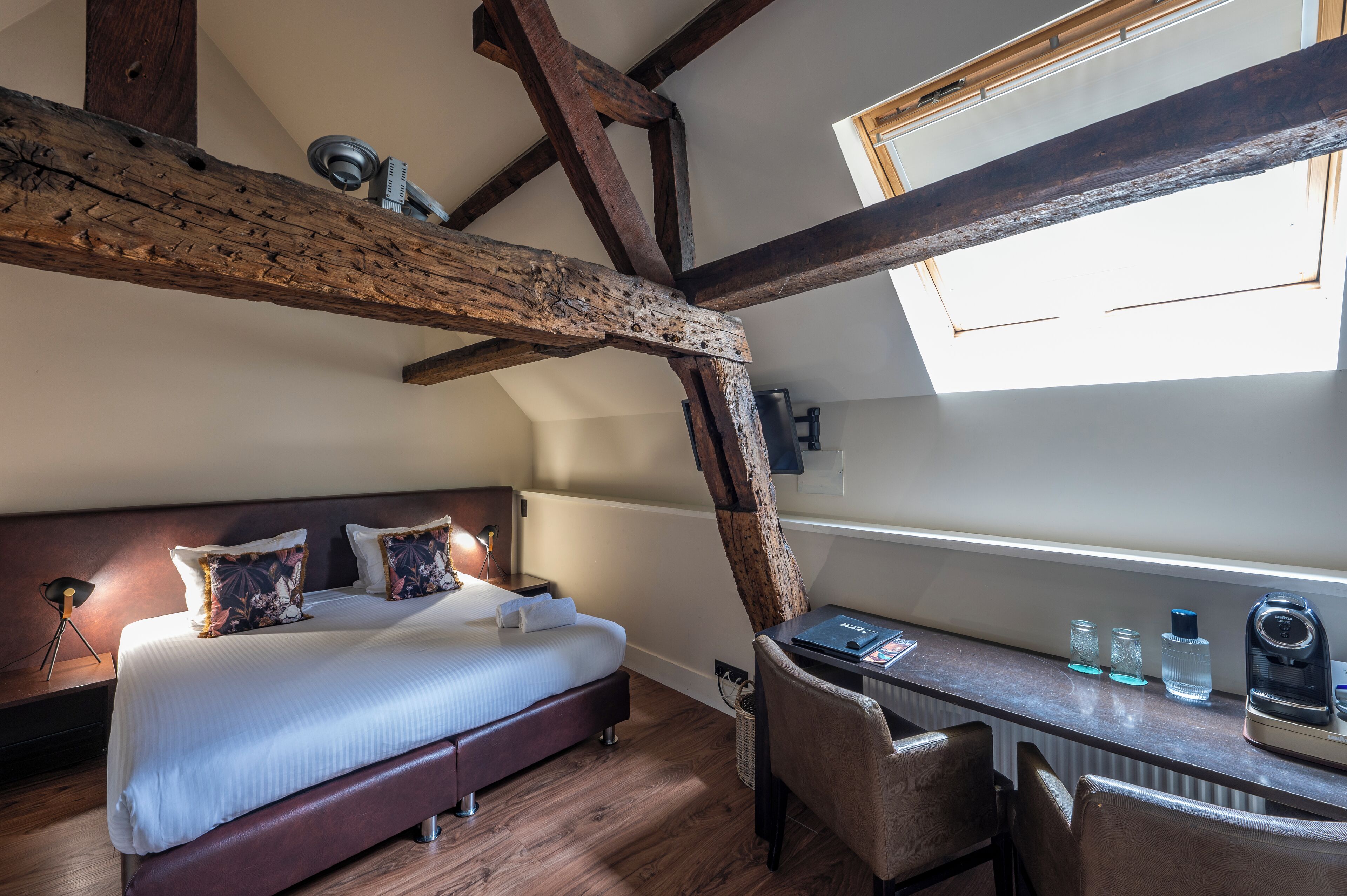 Une chambre avec un grand lit, un bureau et une fenêtre de toit.