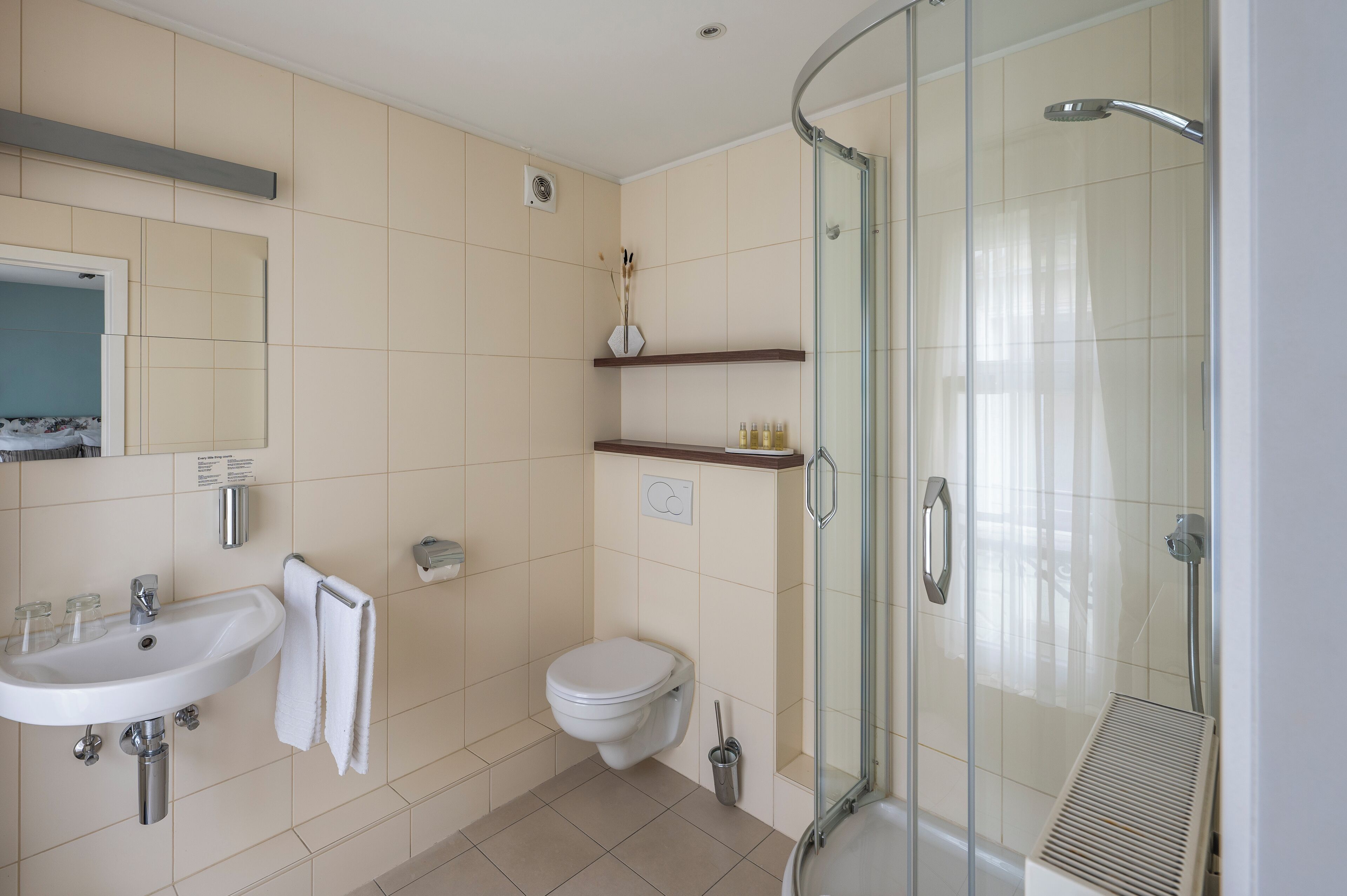 A modern bathroom with a glass-enclosed shower, a sink, and a toilet.
