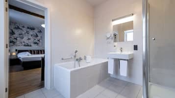 A modern bathroom with a bathtub, a shower, and a sink.